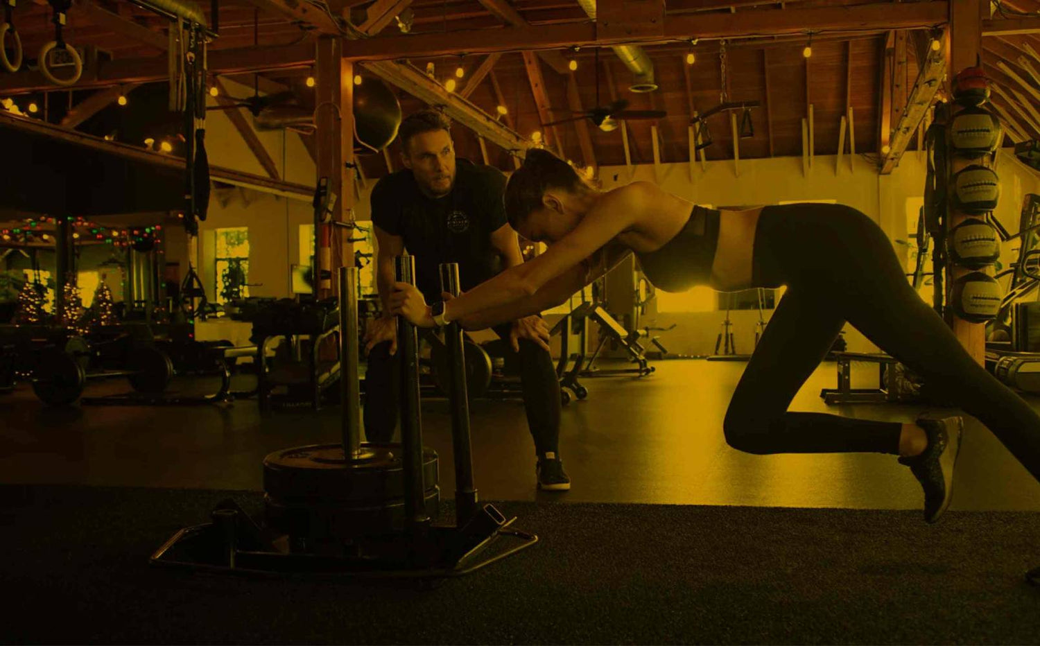 Jason Walsh coaching sled push in his gym (with yellow saturation)