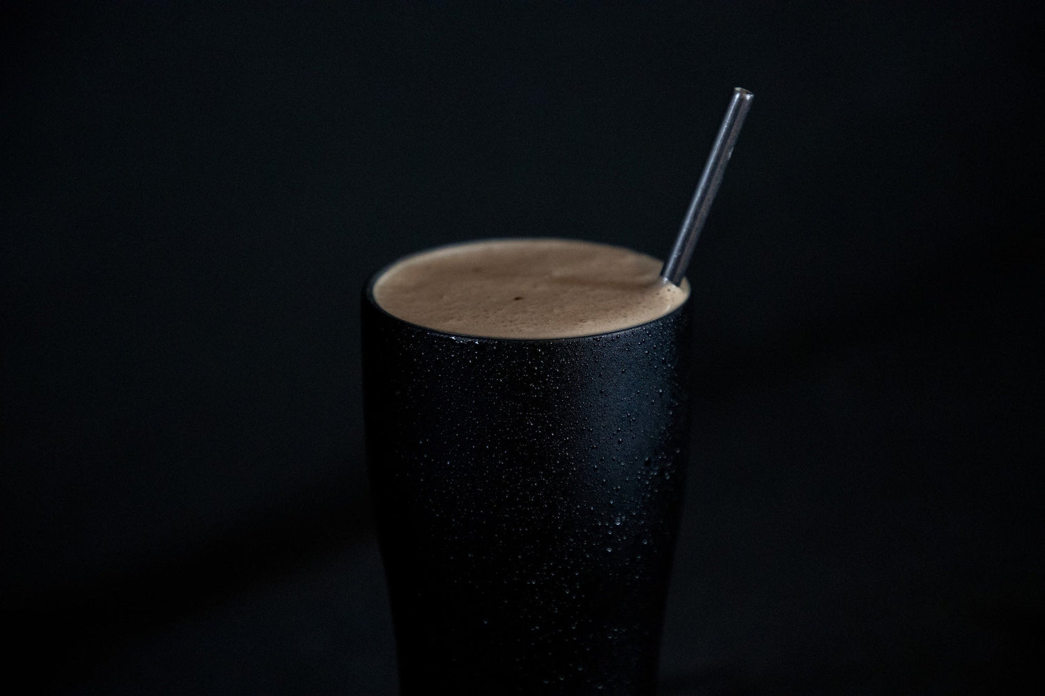 Black stainless steel protein shaker bottle with shake and straw on dark background
