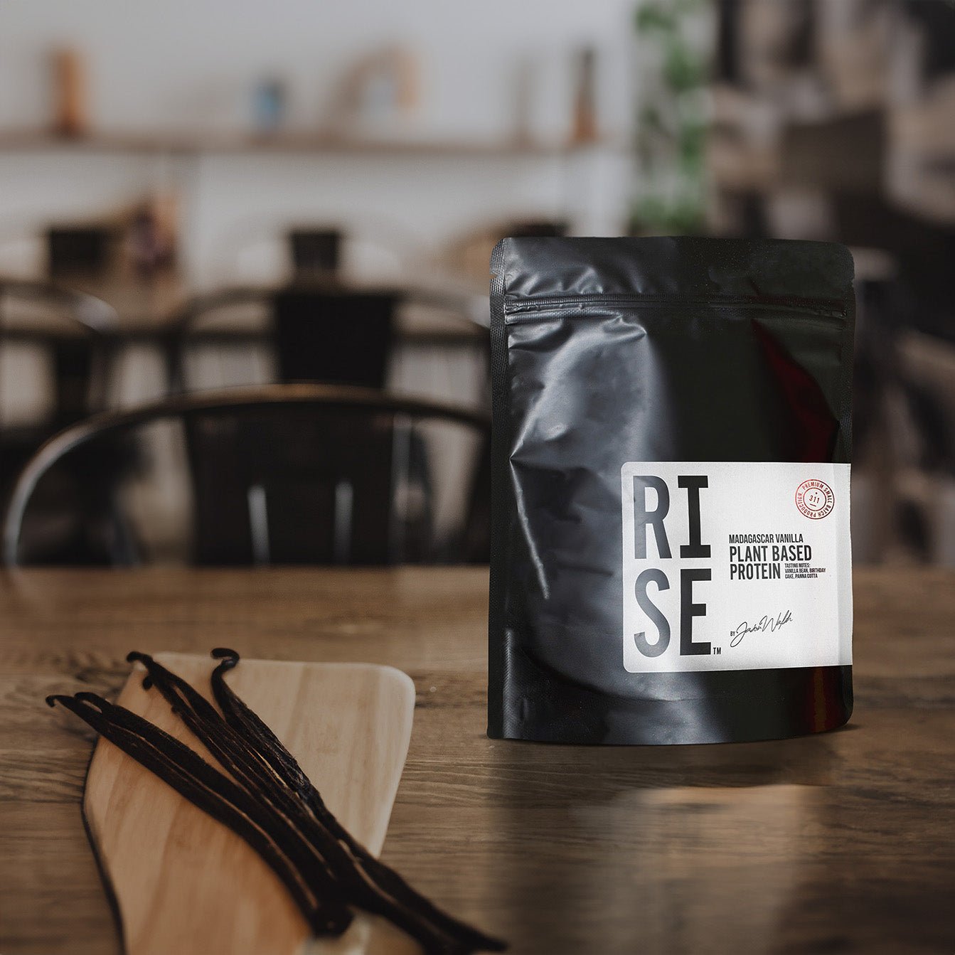 RISE vanilla protein pouch with vanilla beans on wooden table