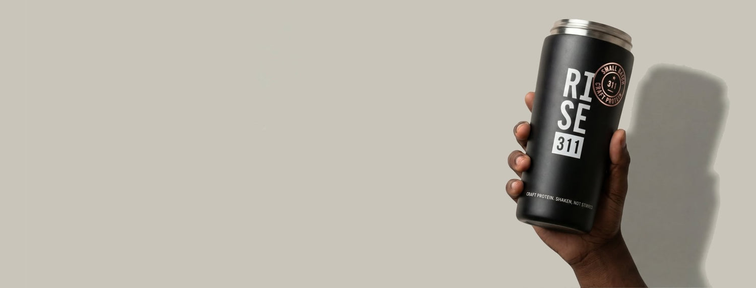 Hand holding RISE protein shaker bottle with shadow on background